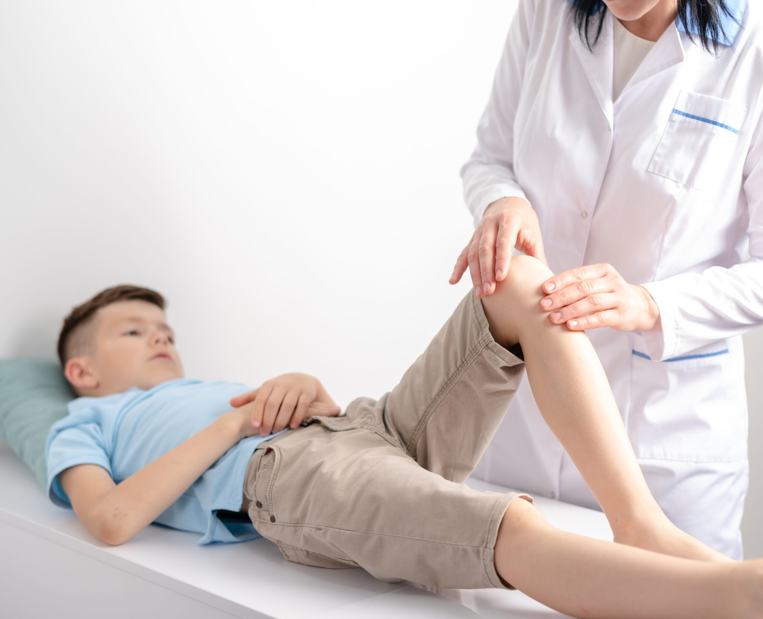Arzt untersucht das Knie eines jungen Patienten